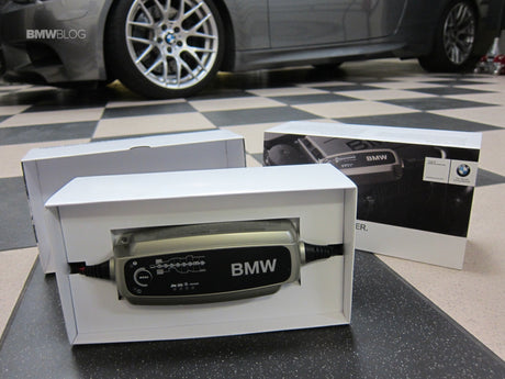 Bmw branded silver and black car battery charger in white packaging for premium car owners in india.
