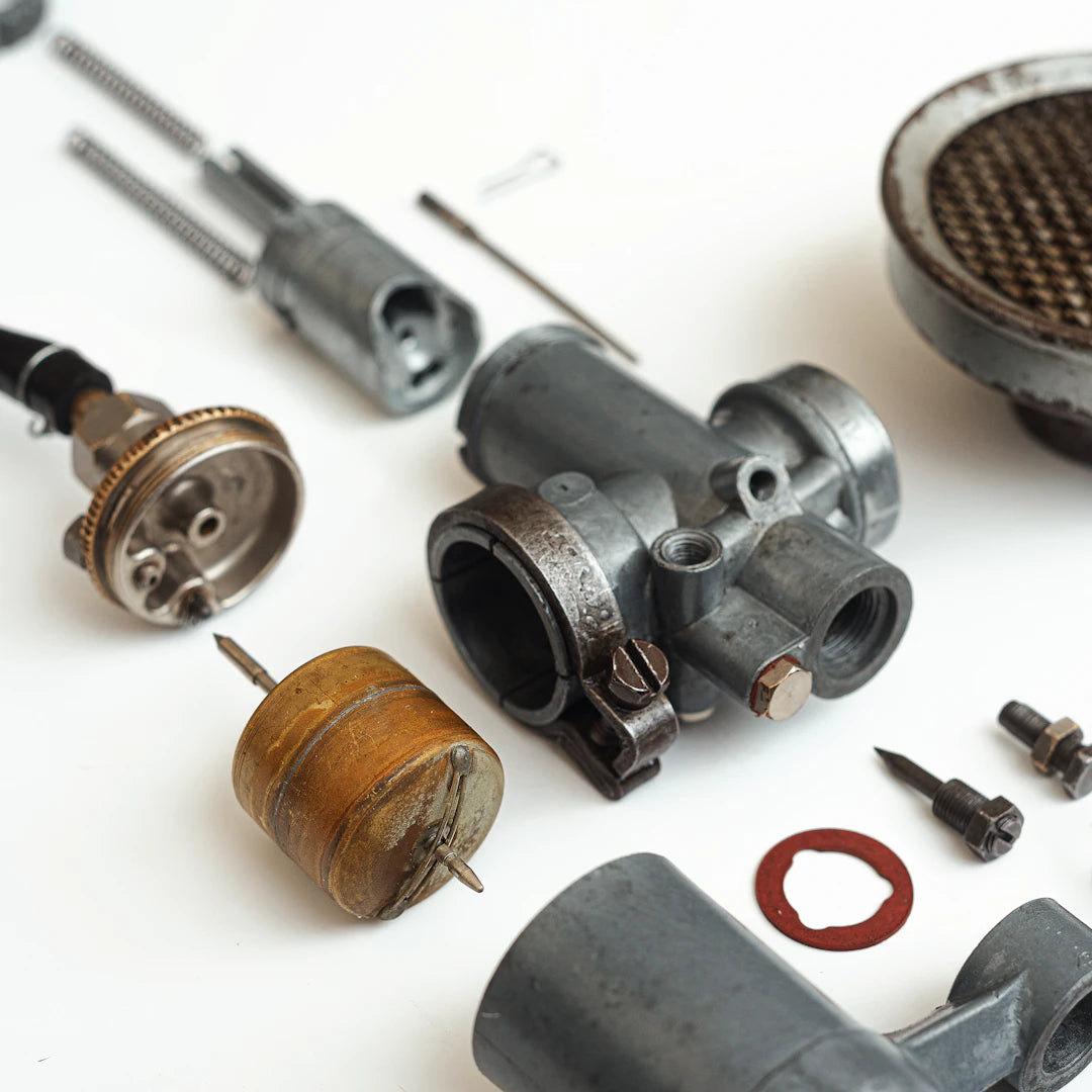 Gray metallic carburetor body with bolts and threaded ports essential for automotive beginners tool guide