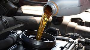 Golden motor oil flows from a white plastic bottle into a black engine oil fill cap in performance additives collection