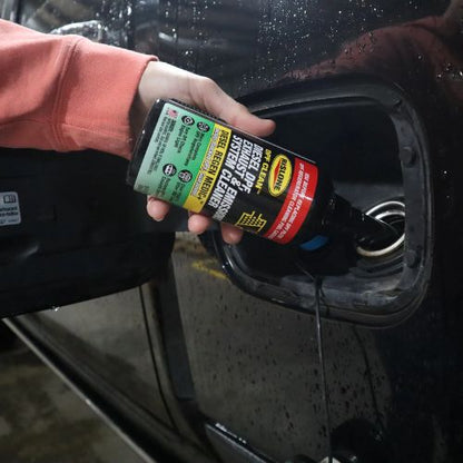 Black bottle of rislone def clean diesel dpf exhaust and emissions system cleaner with green and yellow label poured into car fuel tank
