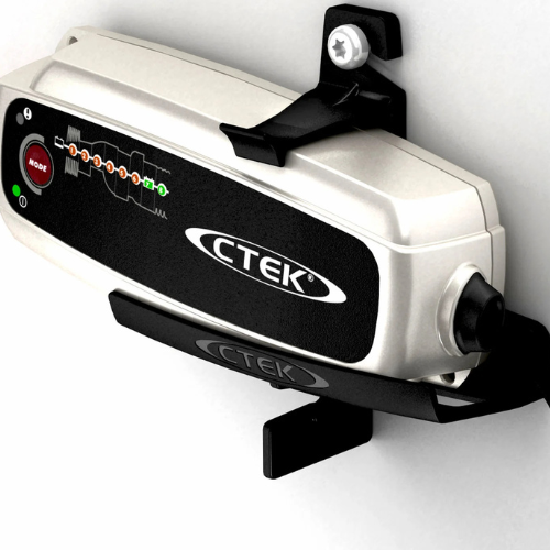 A CTEK battery management system or charger unit in silver and black, mounted on a white wall with black brackets, featuring a red start button and LED indicators.